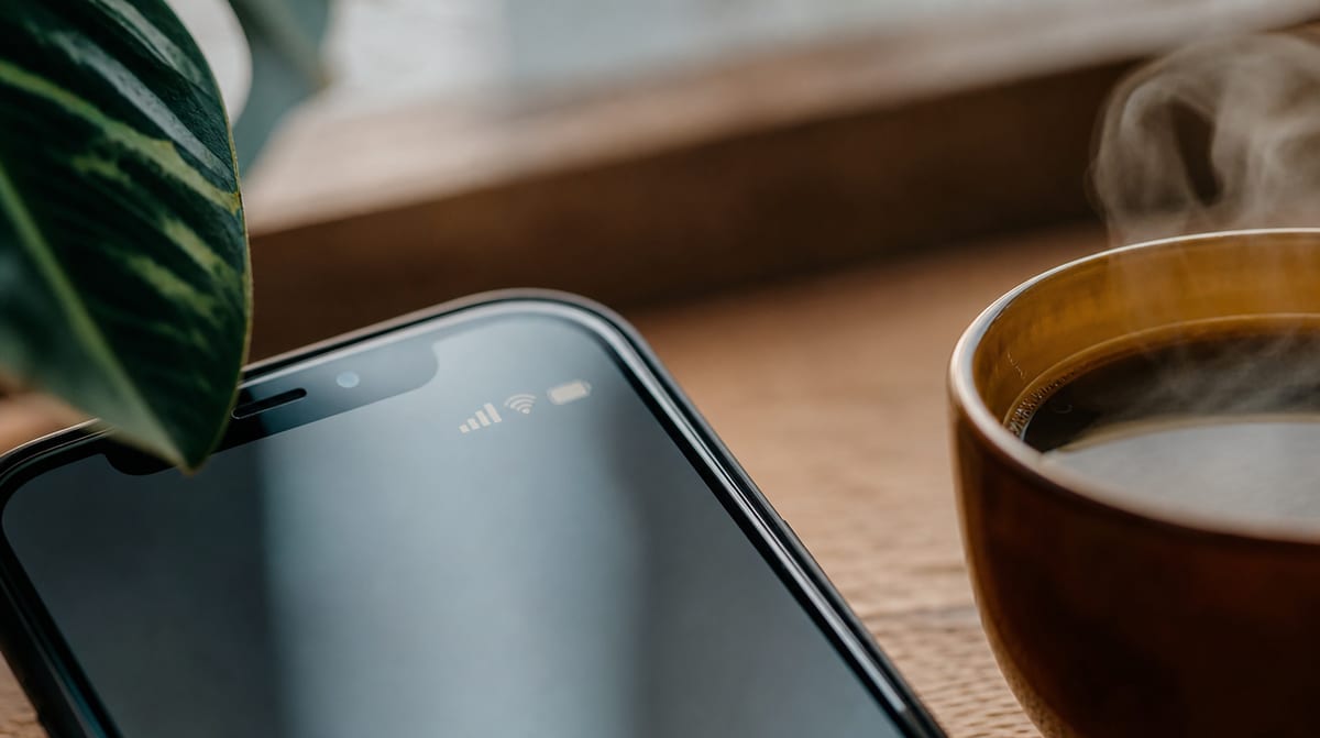 Schermo dello smartphone con icona del segnale di rete su una scrivania in legno – eSIM come si attiva sullo smartphone